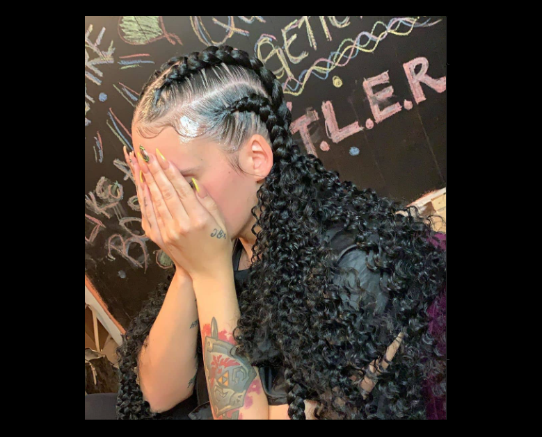 A girl with braids sitting with hands on her face